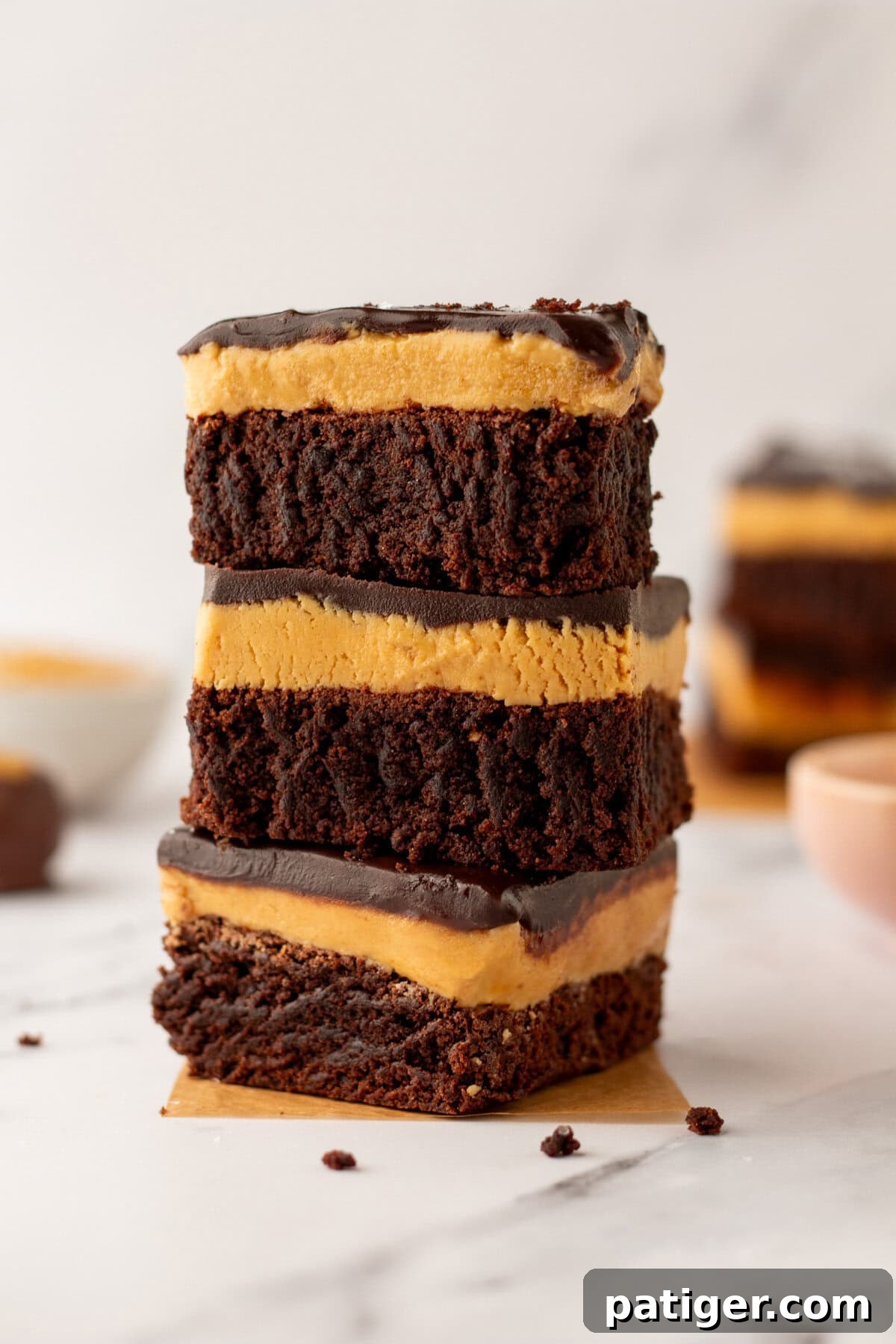 Decadent Buckeye Brownies 3 Stack of three peanut butter chocolate buckeye brownies on parchment paper.