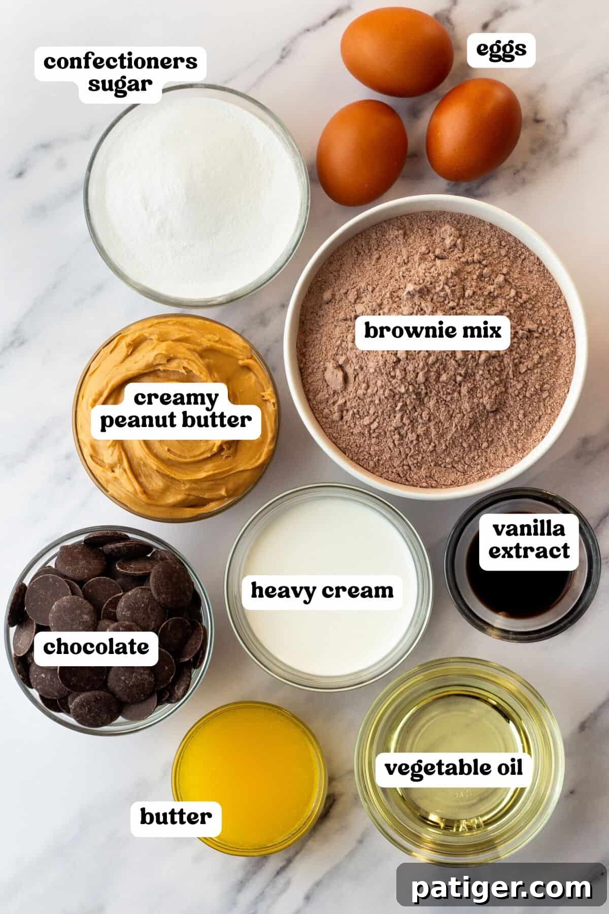 Decadent Buckeye Brownies 4 Flat lay of labeled ingredients in bowls for buckeye brownies, arranged on a marble surface. Items include: confectioners sugar, creamy peanut butter, chocolate, heavy cream, butter, vegetable oil, vanilla extract, brownie mix, and three eggs.