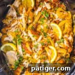 Slow cooker chicken shawarma, featuring marinated shredded chicken, onions, lemon wedges, and garnished with chopped parsley.