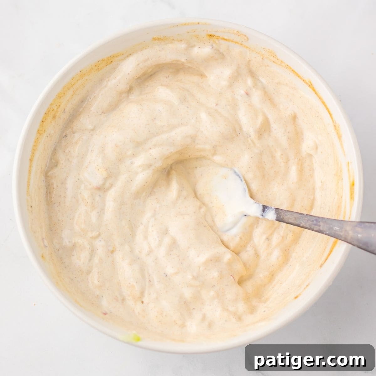 Melt-in-Your-Mouth Slow Cooker Chicken Shawarma 7 Bowl of creamy yogurt sauce with a spoon.