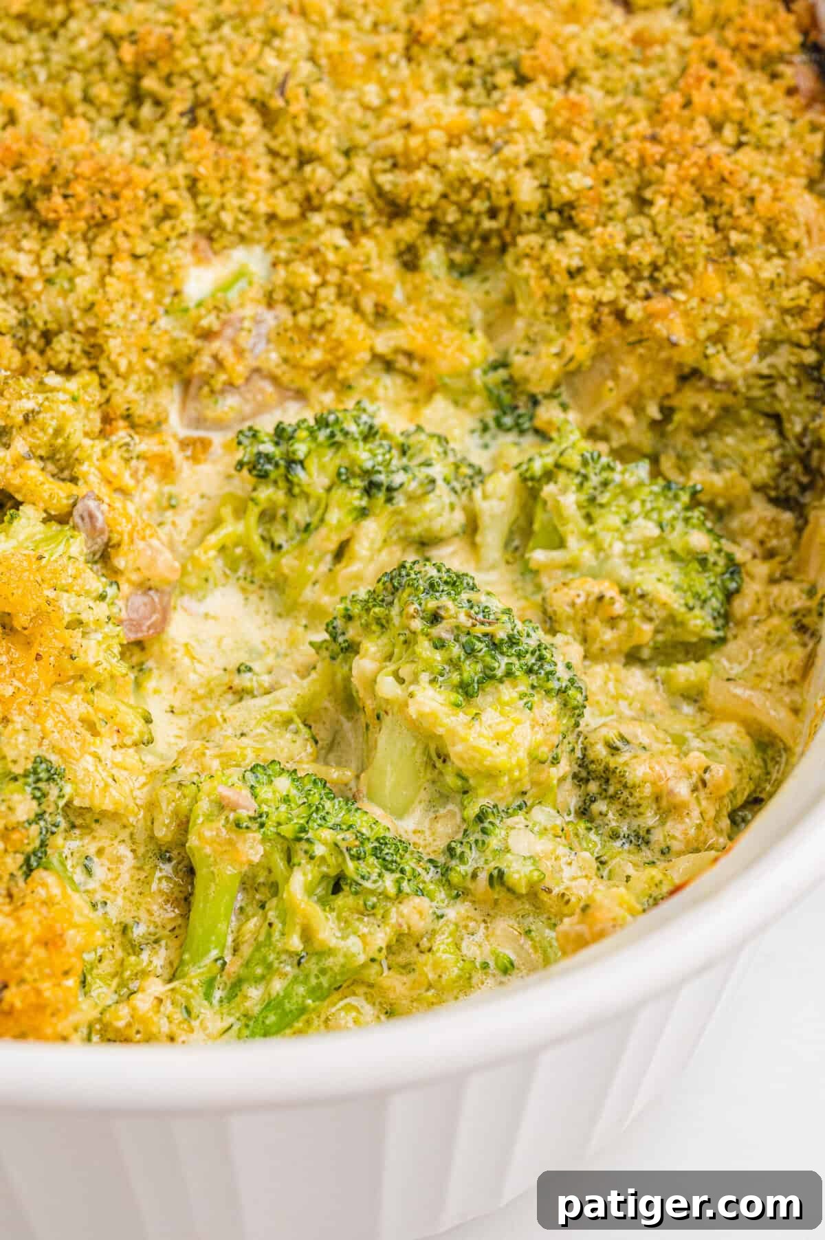 Broccoli casserole in a white dish, showing broccoli florets coated in creamy sauce and melted cheddar cheese with a golden breadcrumb topping.