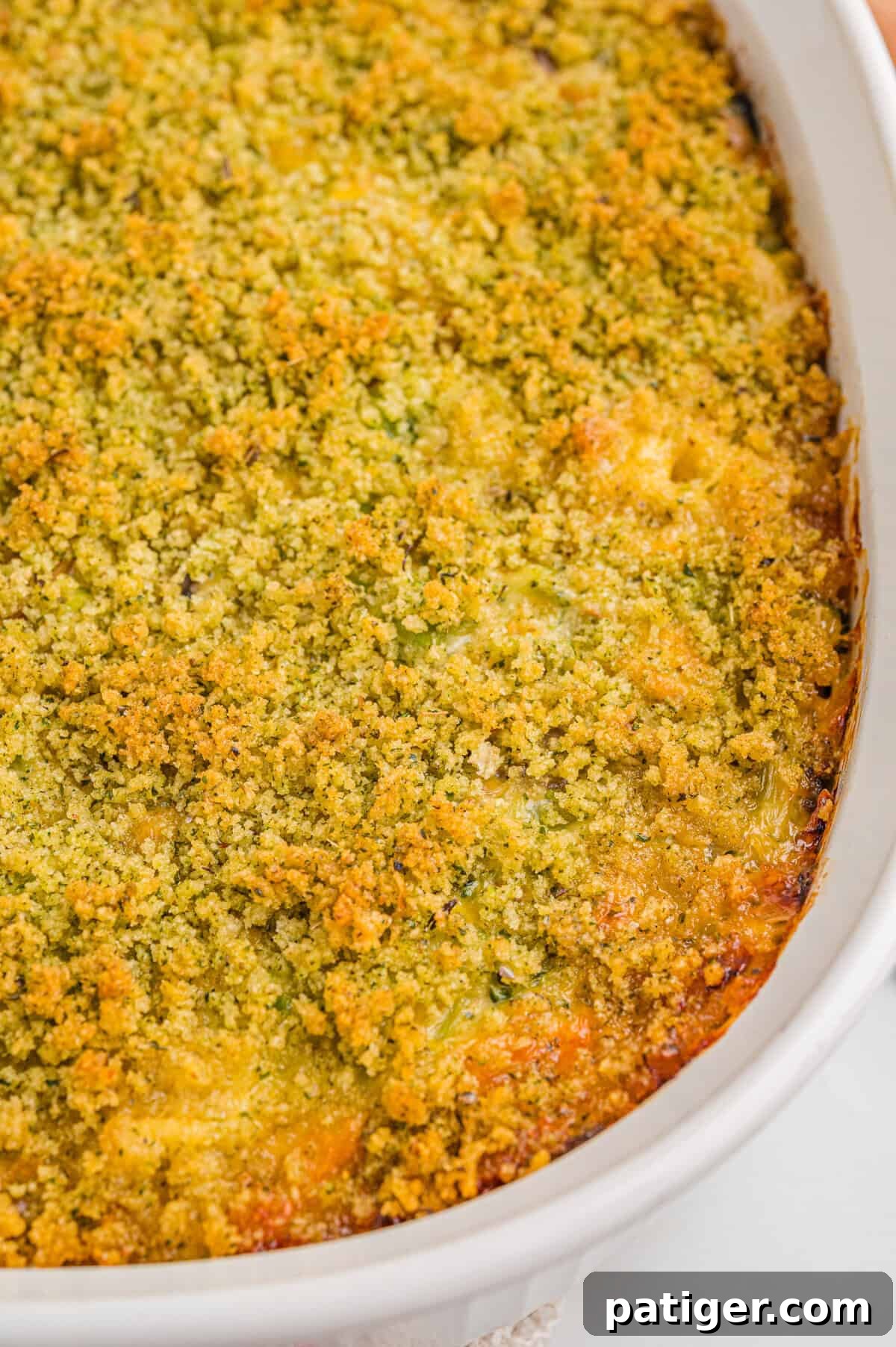 Overhead view of a freshly baked broccoli cheddar casserole in a white dish, with a uniformly browned breadcrumb and cheese topping.