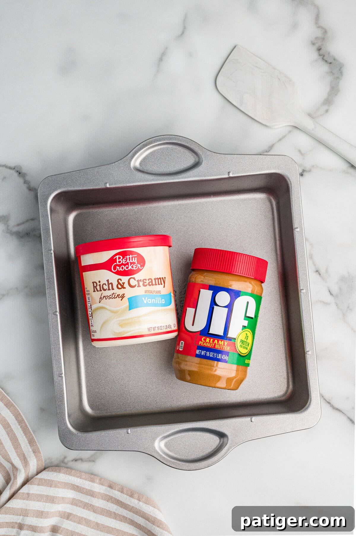 Overhead view of a baking pan containing a jar of Jif creamy peanut butter and a container of Betty Crocker Rich & Creamy vanilla frosting.