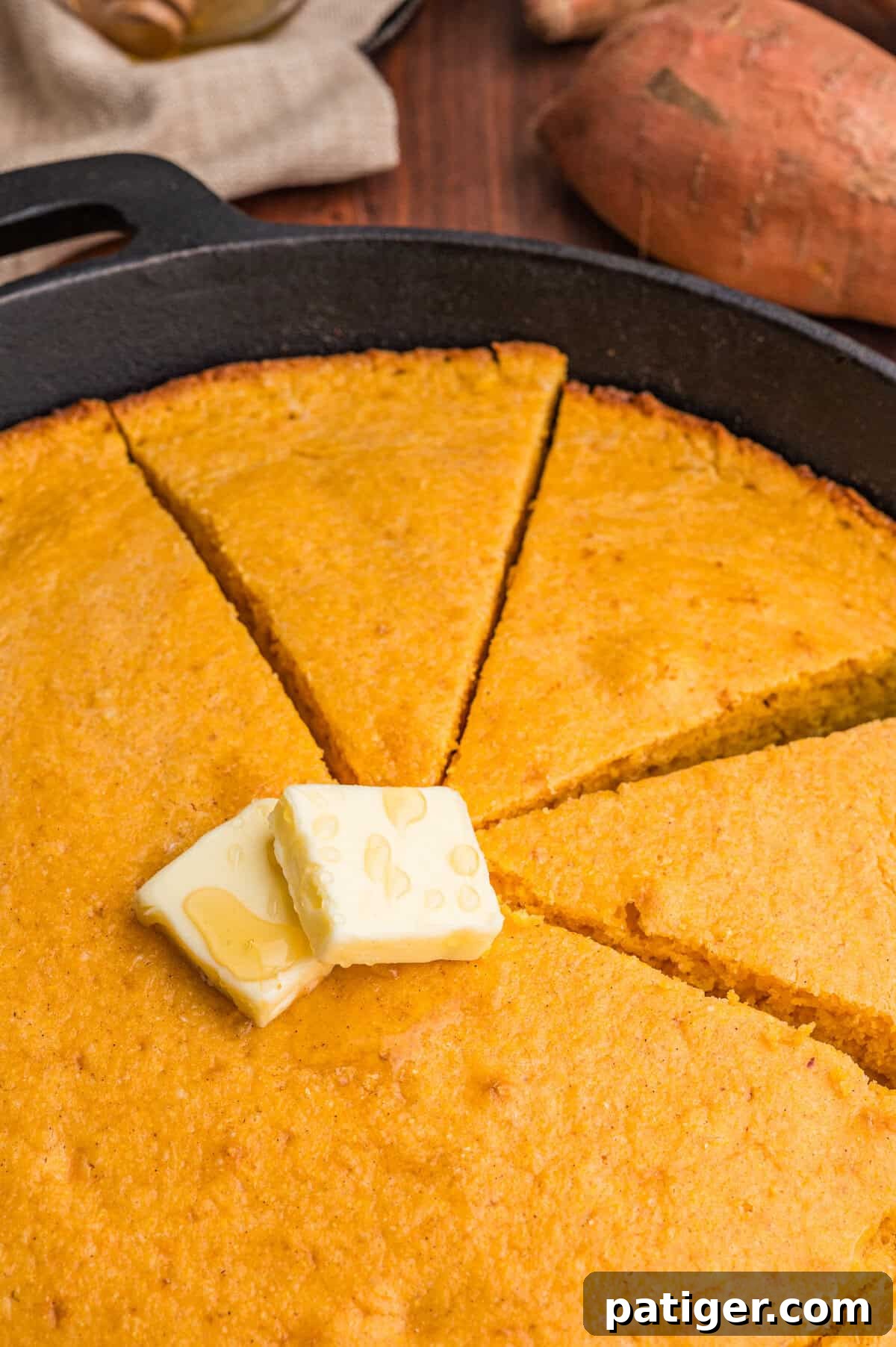 Close-up of sweet potato cornbread wedges topped with butter and honey.