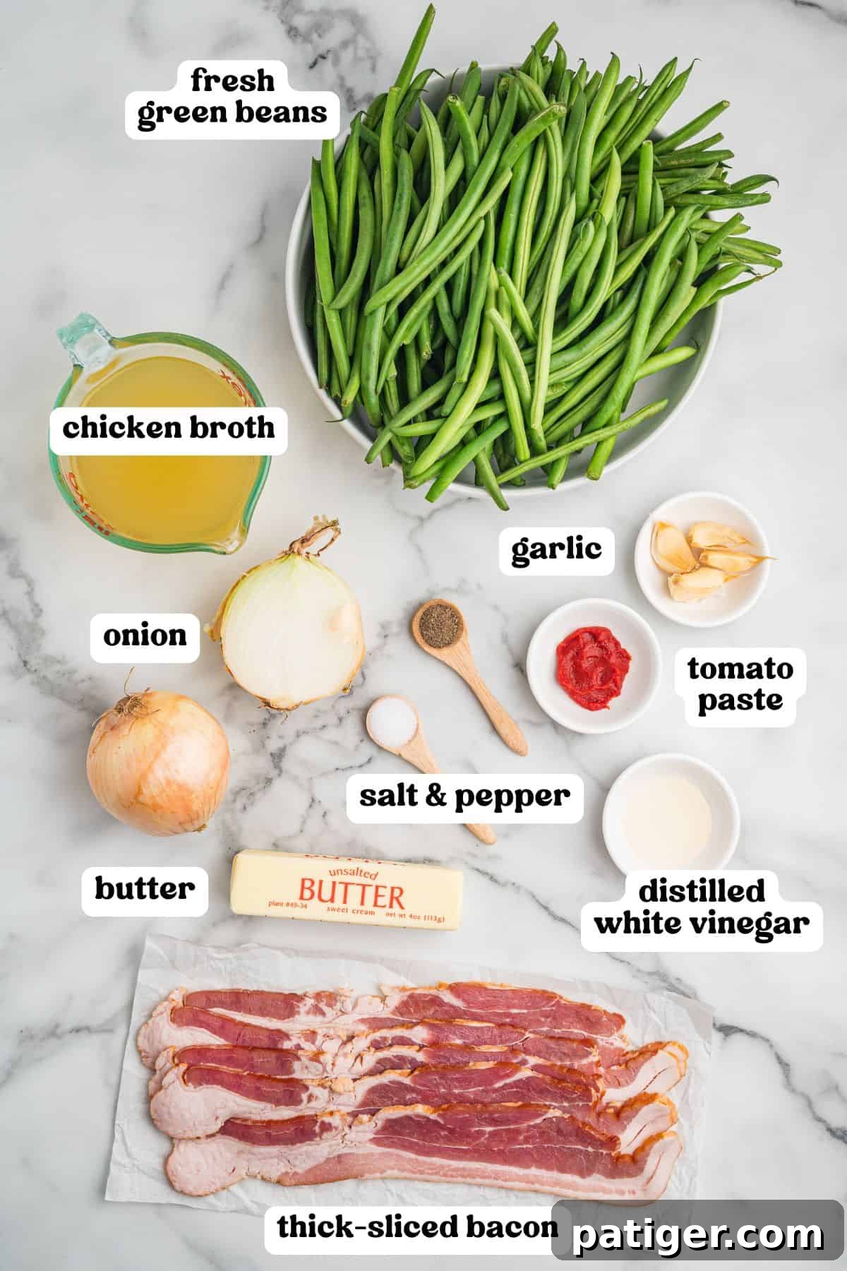 Ingredients for Southern Green Beans with Bacon, including fresh green beans, chicken broth, onion, butter, thick-sliced raw bacon, garlic cloves, tomato paste, salt, pepper, and distilled white vinegar.