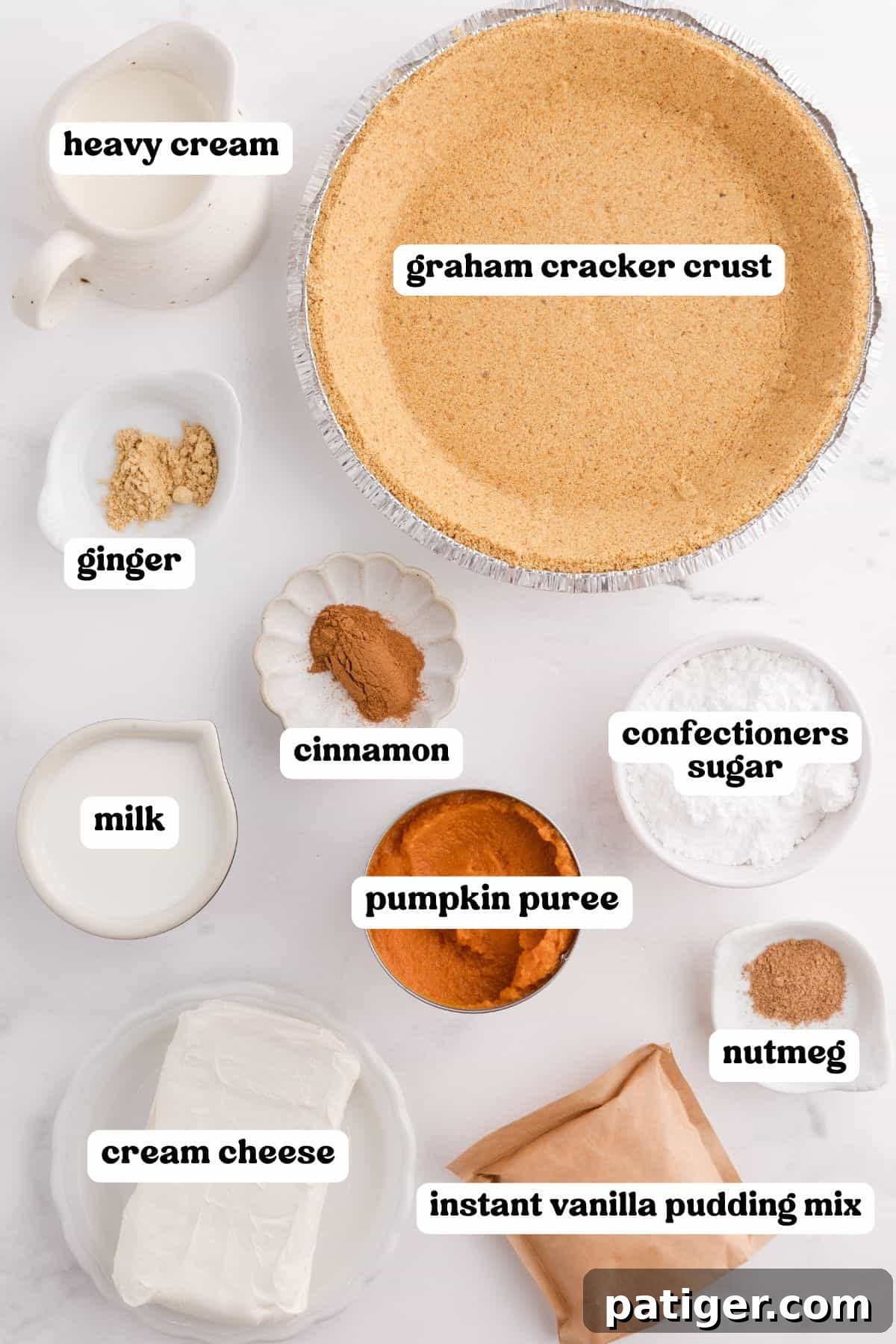 Velvety No-Bake Pumpkin Pie Bliss 4 Carefully arranged ingredients for the no-bake pumpkin pie on a pristine white background. Items include heavy cream, a ready-made graham cracker crust, ground ginger, milk, ground cinnamon, pumpkin purée, softened cream cheese, instant vanilla pudding mix, confectioners' sugar, and ground nutmeg, all labeled for clarity.