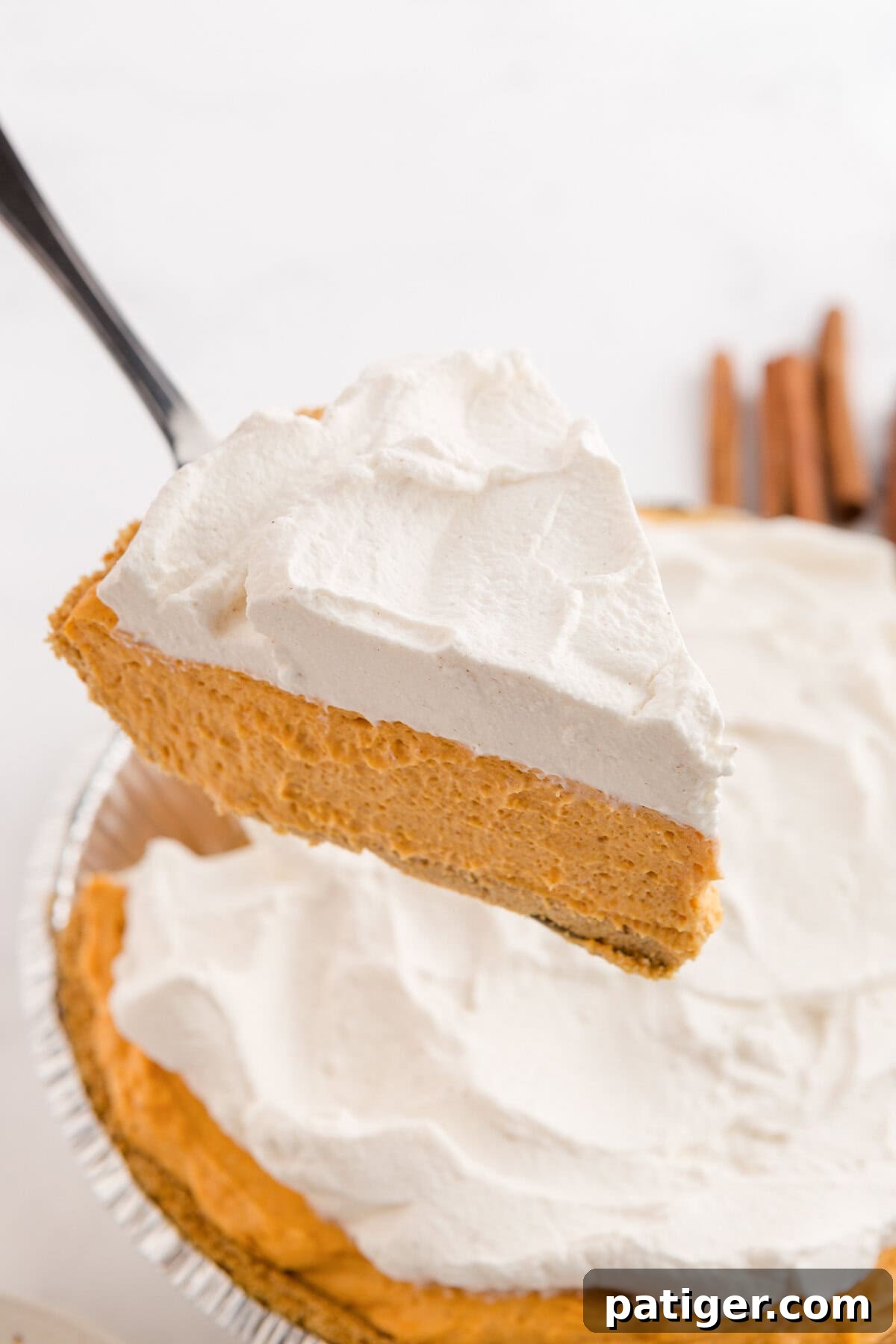 Velvety No-Bake Pumpkin Pie Bliss 8 A pristine slice of no-bake pumpkin pie being carefully lifted from the pie pan, showcasing its firm, creamy texture and ready-to-serve presentation.