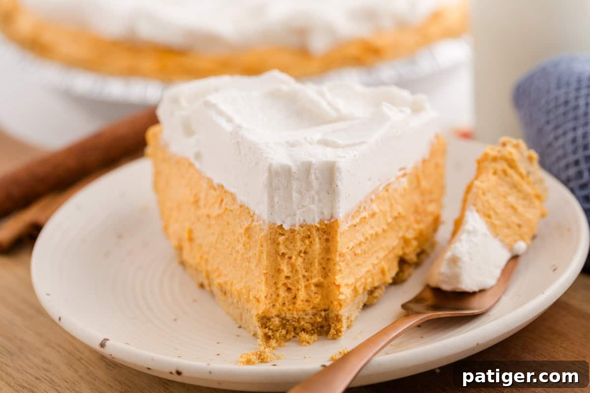 Velvety No-Bake Pumpkin Pie Bliss 9 A mouthwatering slice of no-bake pumpkin pie on a white plate, with a fork holding a perfect bite, highlighting the creamy texture and inviting layers.