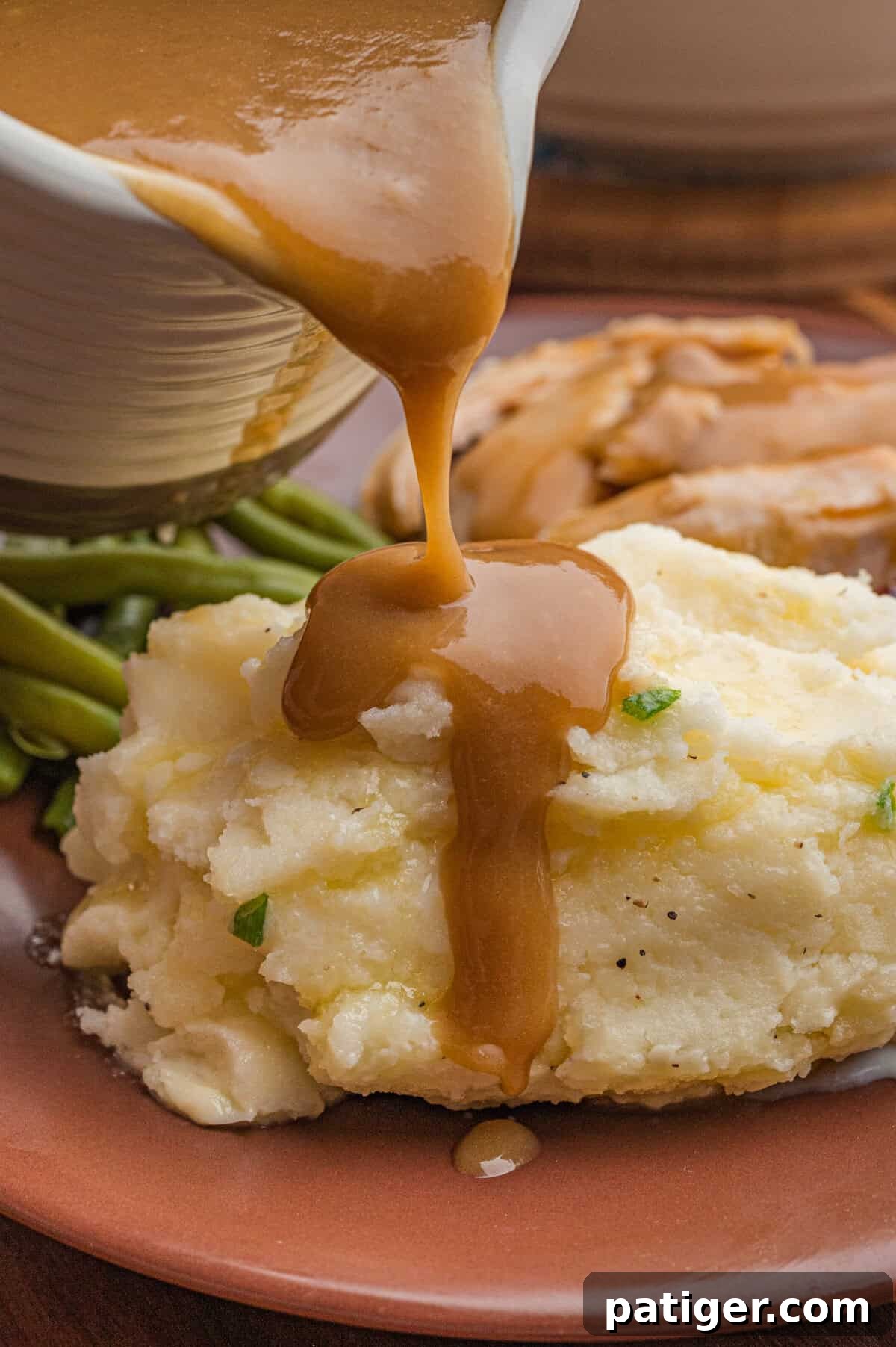 Gravy being poured over classic mashed potatoes.