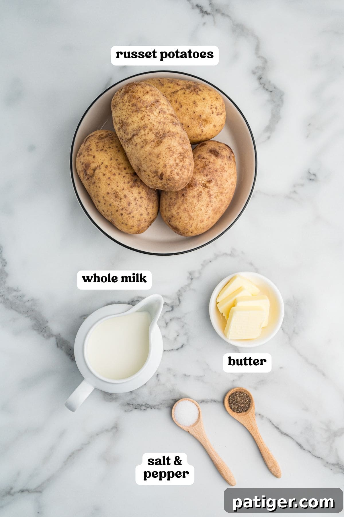 Labeled ingredients: a bowl of russet potatoes, a small pitcher of whole milk, a dish of butter slices, and two wooden spoons with salt and pepper.
