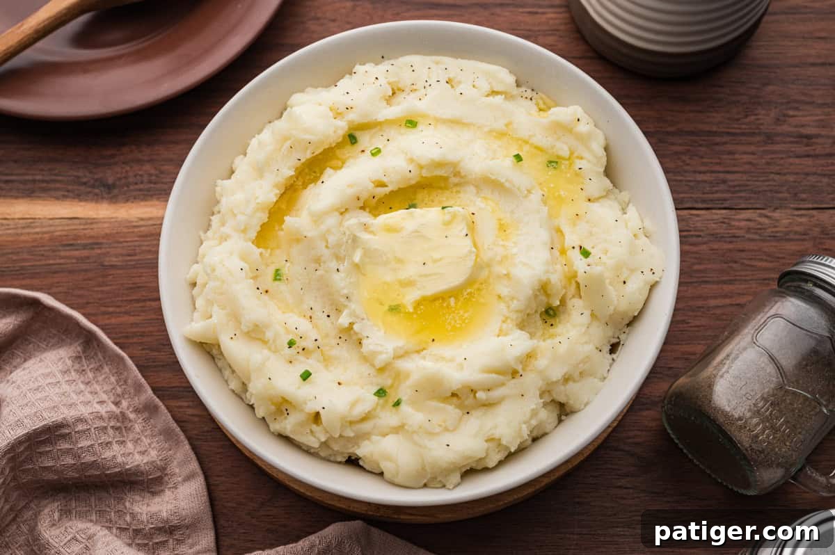 Bowl of old fashioned mashed potatoes topped with a pat of butter.