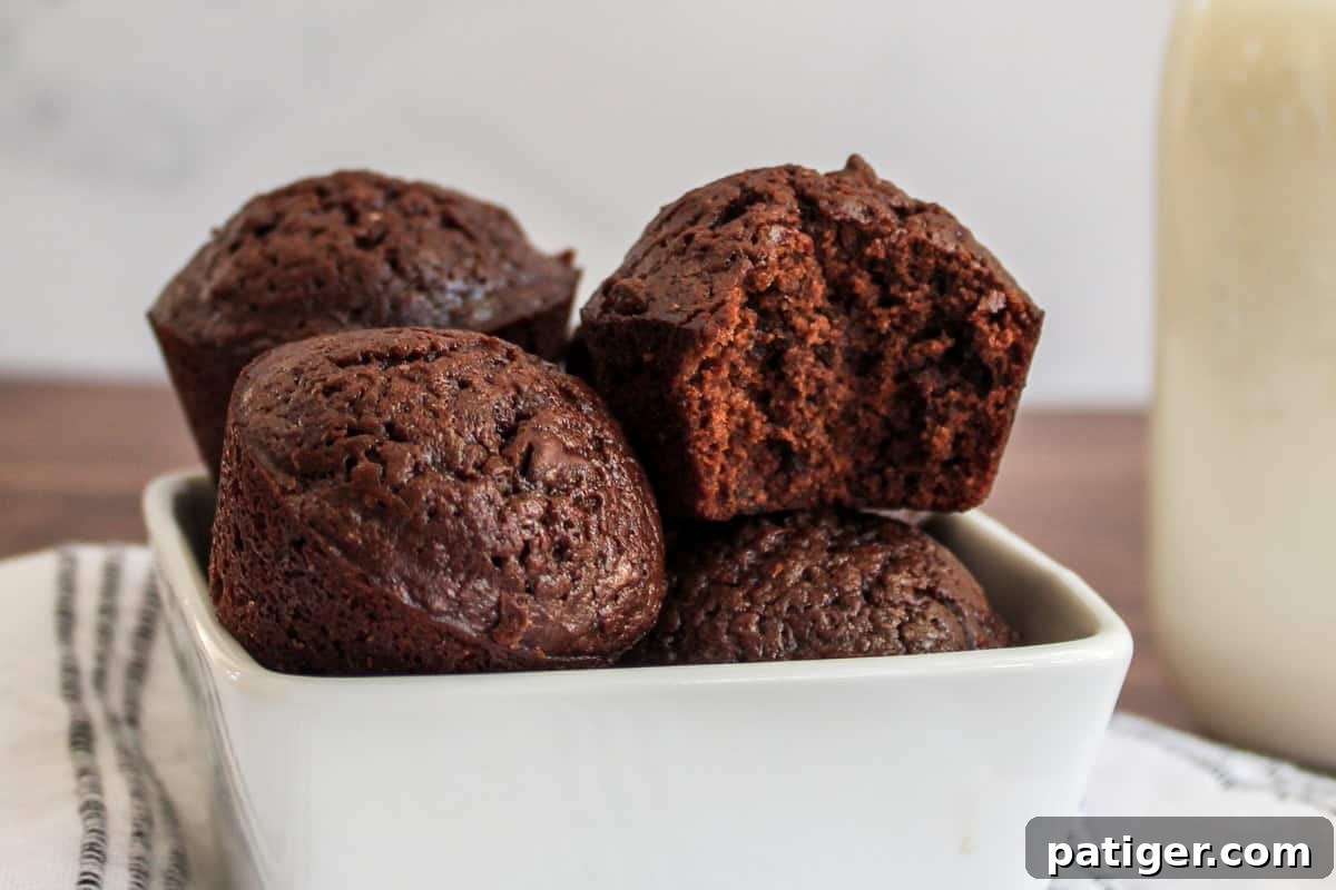 Bite-Sized Brownie Bliss 2 Close-up of several chocolate brownie bites in a white bowl, one brownie bite has a bite taken out of it.