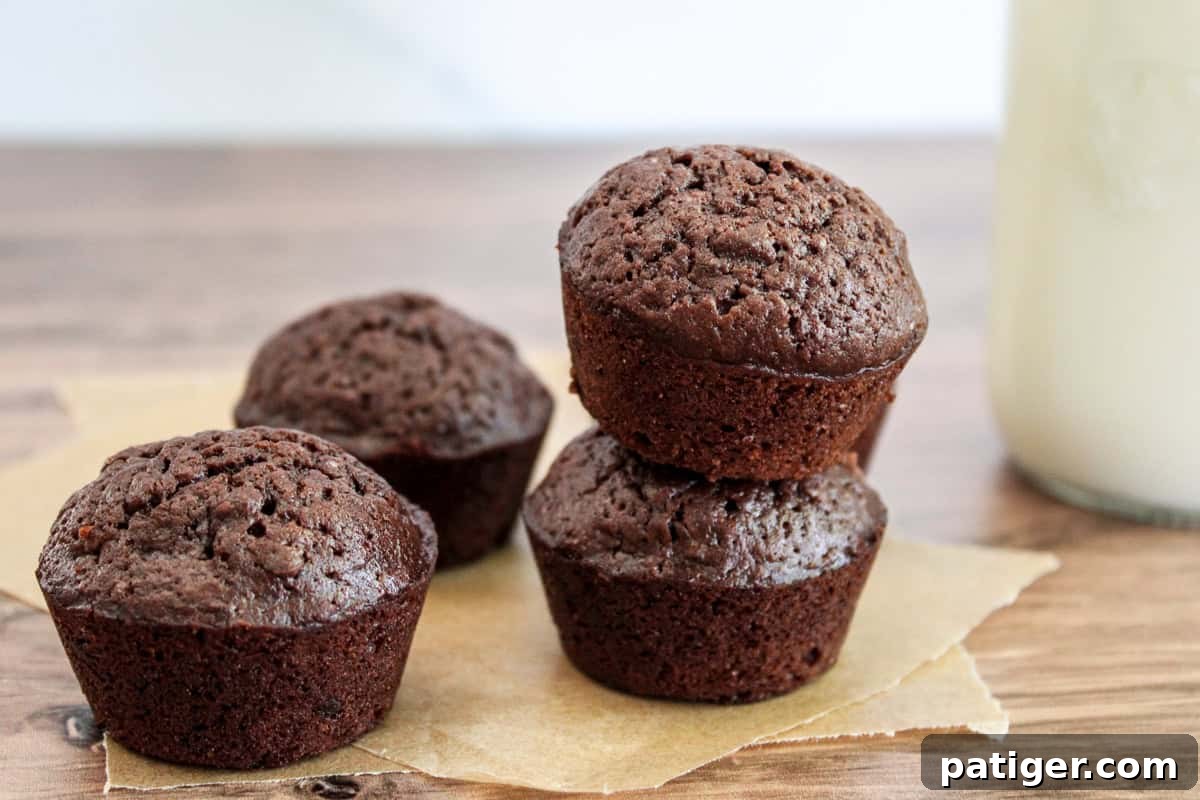 Bite-Sized Brownie Bliss 6 Four mini muffin brownie bites on parchment with a milk bottle in the background.