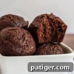 Bite-Sized Brownie Bliss 8 Close-up of several chocolate brownie bites in a white bowl, one brownie bite has a bite taken out of it.