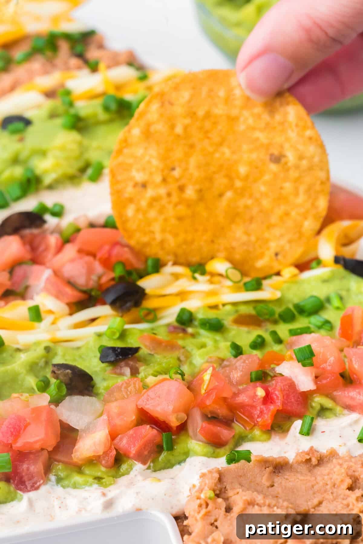 Hand dipping chip into Christmas 7 layer taco dip.