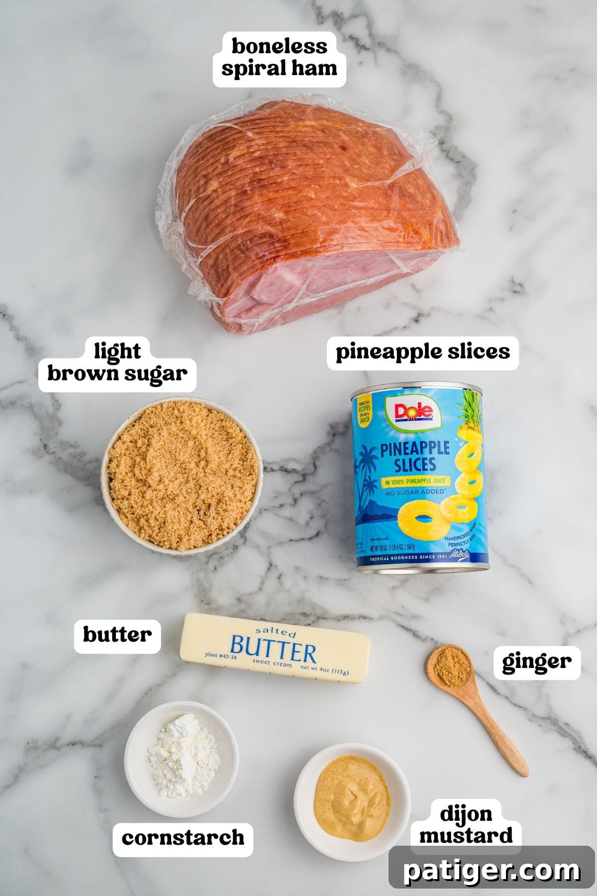 Irresistible Slow Cooker Ham with Pineapple Brown Sugar Glaze 4 A well-organized flat lay of ingredients on a pristine marble surface, arranged for preparing a delicious boneless spiral ham. The collection includes a neatly wrapped spiral ham, a bright can of sliced pineapple, a bowl of rich light brown sugar, a stick of golden salted butter, a spoonful of aromatic ground ginger, a small dish of cornstarch for thickening, and a bowl of tangy Dijon mustard. Each ingredient is clearly labeled with bold, contrasting black and white text for easy identification.