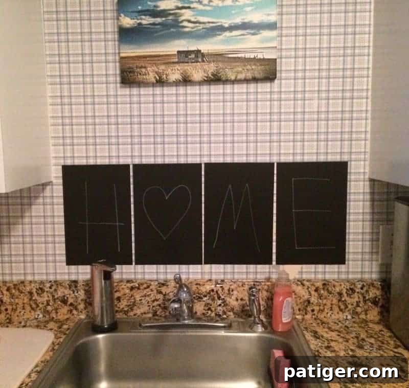 A close-up shot of black chalkboard stickers spelling "home" positioned above the kitchen sink, adding a temporary decorative touch.
