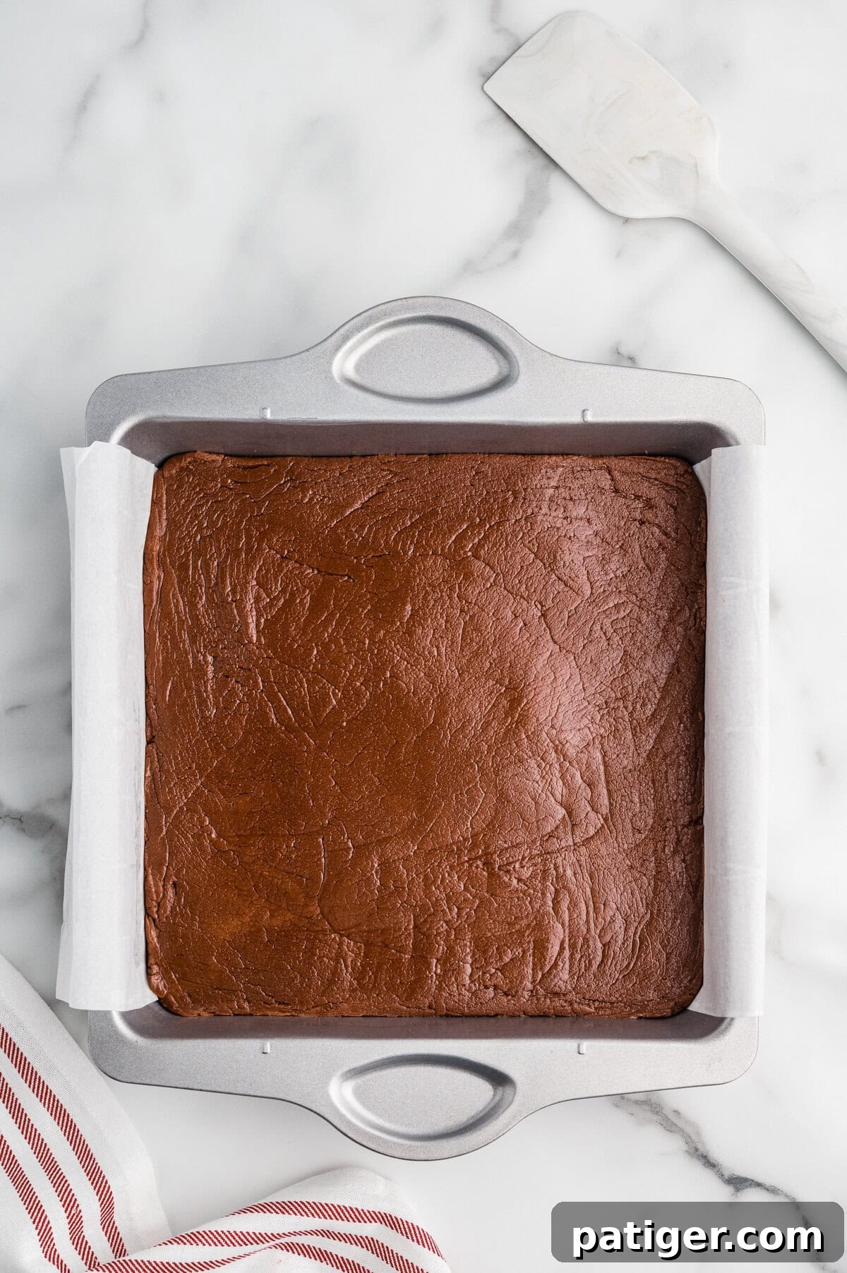 Chocolate fudge in a square parchment-lined pan.