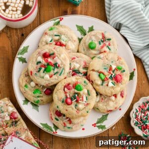 Overhead view of Christmas M&M cookies with white chocolate chips and sprinkles on a holiday plate.