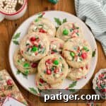 Overhead view of Christmas M&M cookies with white chocolate chips and sprinkles on a holiday plate.