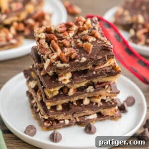 Stacked pieces of saltine cracker toffee with pecans on top.