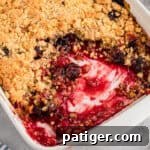 Cherry cobbler with cake mix in a white baking dish, showing a golden crumbly topping and a cherry filling.