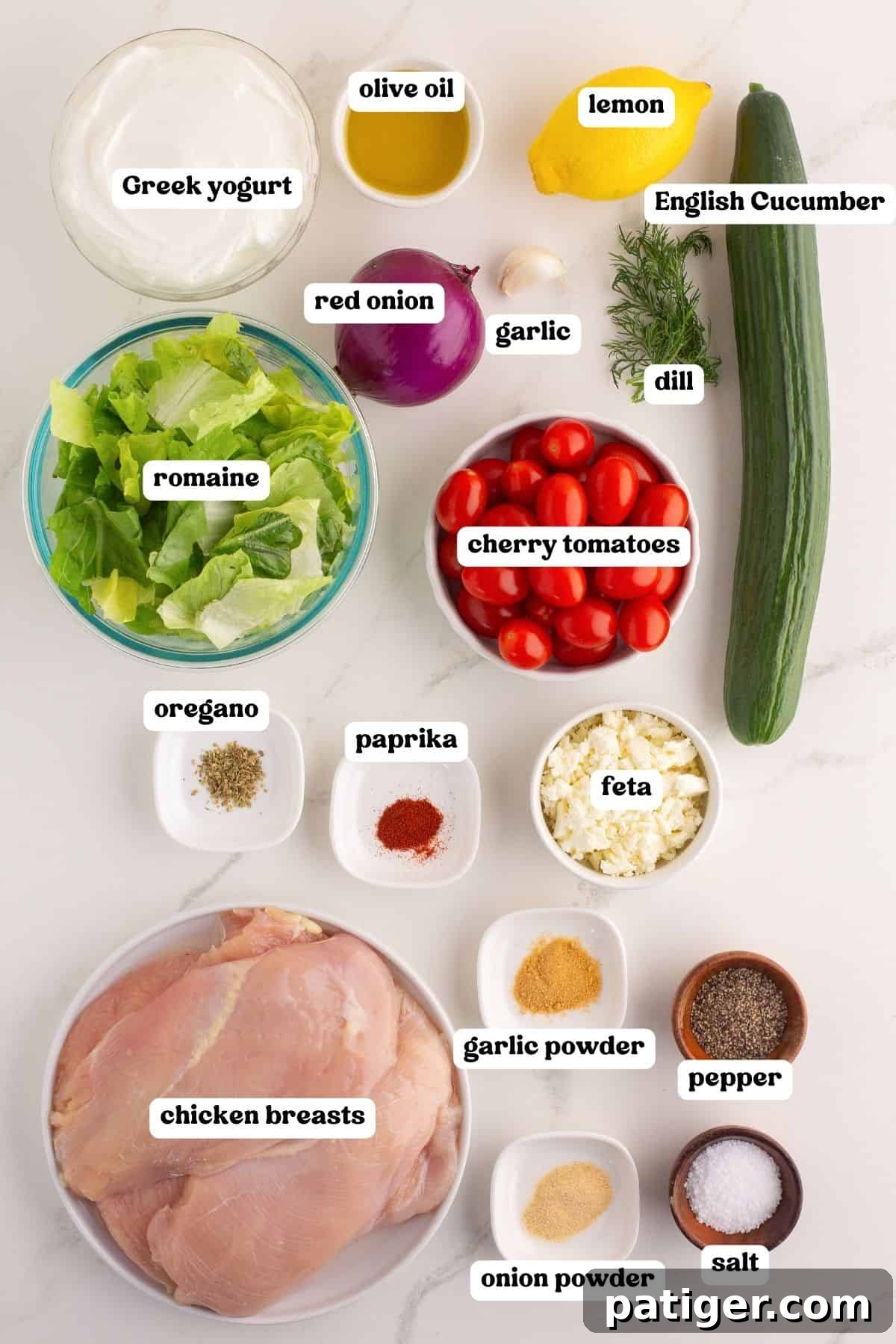 An organized display of all the fresh ingredients required for Greek chicken gyro bowls, each element clearly labeled. Featured ingredients include creamy Greek yogurt, golden olive oil, bright lemon, crisp English cucumber, sharp red onion, pungent garlic, fresh dill, sweet cherry tomatoes, crunchy romaine, fragrant oregano, sweet paprika, crumbly feta, lean chicken breasts, and essential spices like garlic powder, onion powder, pepper, and salt.