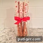 White chocolate dipped Valentine's Day pretzel rods with heart sprinkles.