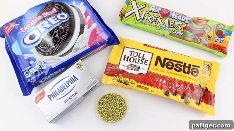 Close-up of ingredients for St. Patrick's Day Pot Of Gold Oreo Truffles including cream cheese, Oreos, chocolate chips, gold sugar pearls, and rainbow candy.