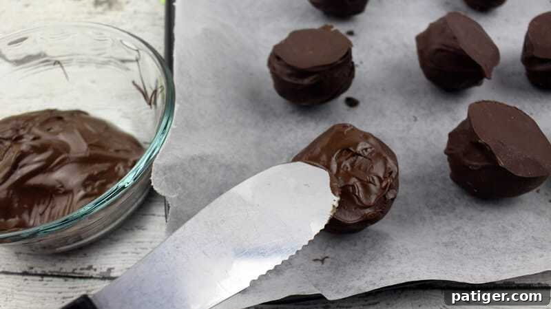 Melted chocolate being delicately spread onto the flat, inverted side of a truffle, preparing it for festive St. Patrick's Day decorations.