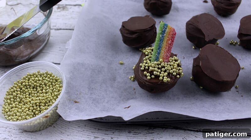 A finished Pot of Gold Oreo truffle, adorned with gold ball sprinkles covering the remaining melted chocolate and a vibrant rainbow candy.
