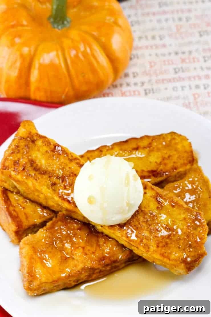 Pumpkin French toast sticks served on white plate with a round scoop of butter and maple syrup poured on top.