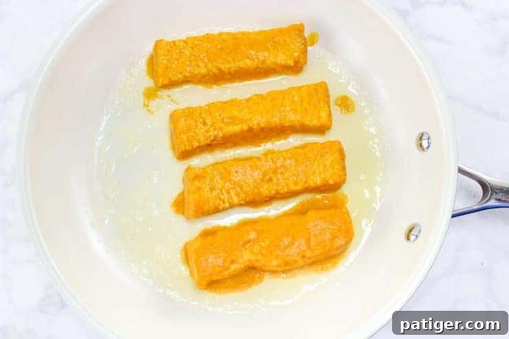 Battered bread sticks in frying pan.