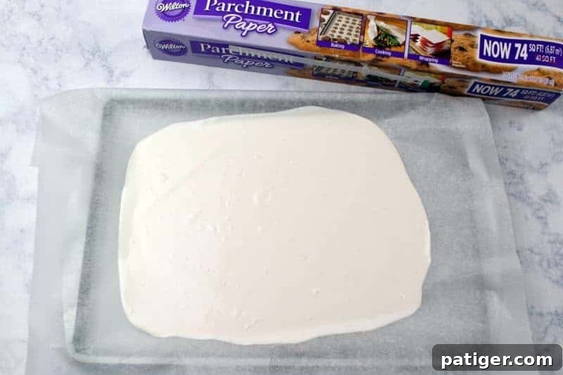 Melted white candy pour onto parchment lined baking sheet.