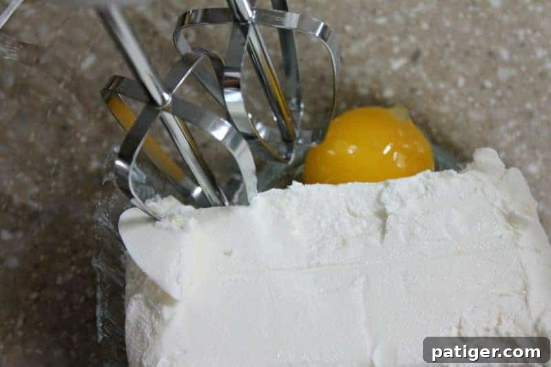 Cream cheese and egg yolk being beaten together in a small bowl for the filling.