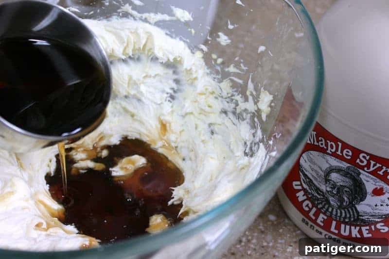 Maple flavoring and maple syrup being added to the cream cheese mixture.
