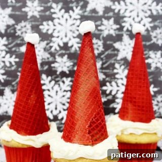 Santa hat cupcakes are made by topping cupcakes with red sugar cones and a mini marshmallow. These fun and easy Christmas cupcakes will definitely be a hit!