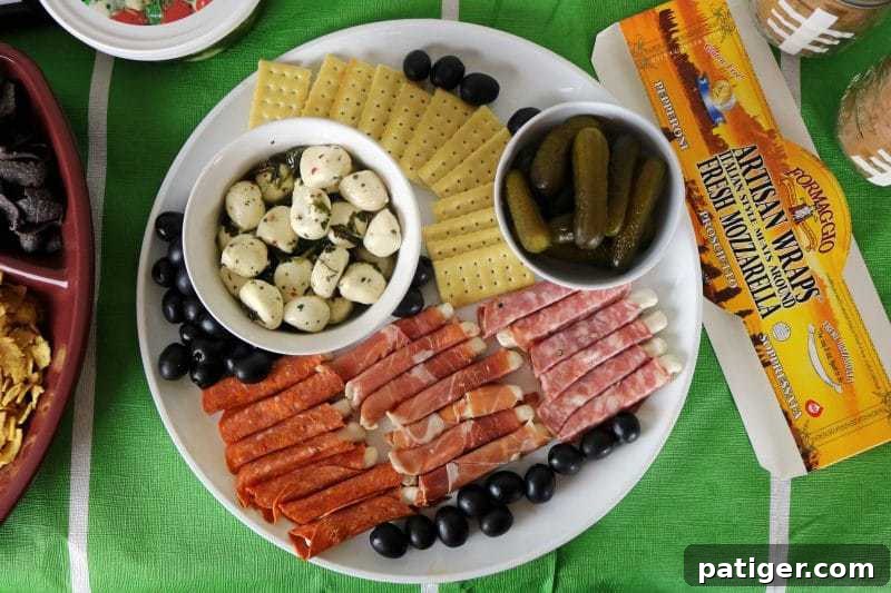 A beautifully arranged Game Day charcuterie board with Italian cheeses, crackers, olives, and pickles.
