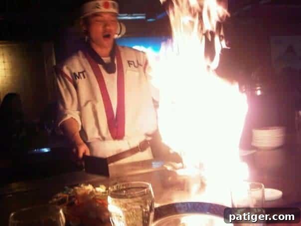 A skilled Hibachi chef creating a 'fire in the hole' flame spectacle at Mt. Fuji Japanese restaurant in Hasbrouck Heights, entertaining diners.