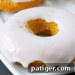 Baked pumpkin doughnuts served warm and smothered with glaze are the perfect Fall recipe for breakfast and dessert alike.
