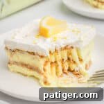 Layered lemon pudding, graham cracker, and cool whip dessert topped with a fresh lemon slice.