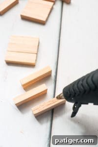 Hot glue gun applying glue to wood blocks