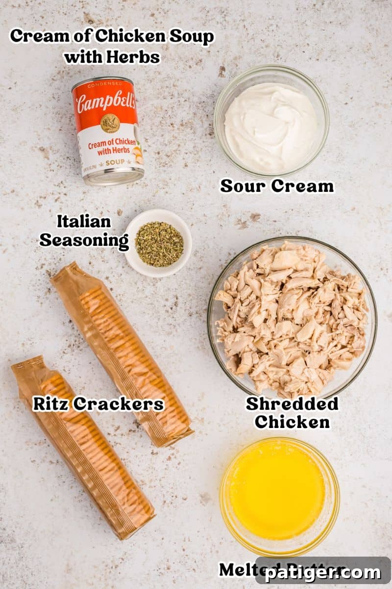 Can of cream of chicken with herbs condensed soup, sour cream, Italian seasoning, melted butter, two sleeves of ritz crackers, and shredded chicken arranged on a surface for ingredient display.