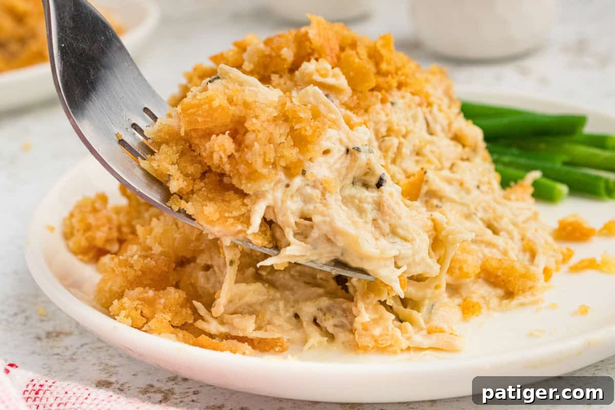Fork taking fokfull of creamy ritz cracker chicken casserole off of plate, showing the creamy chicken and crunchy topping. 