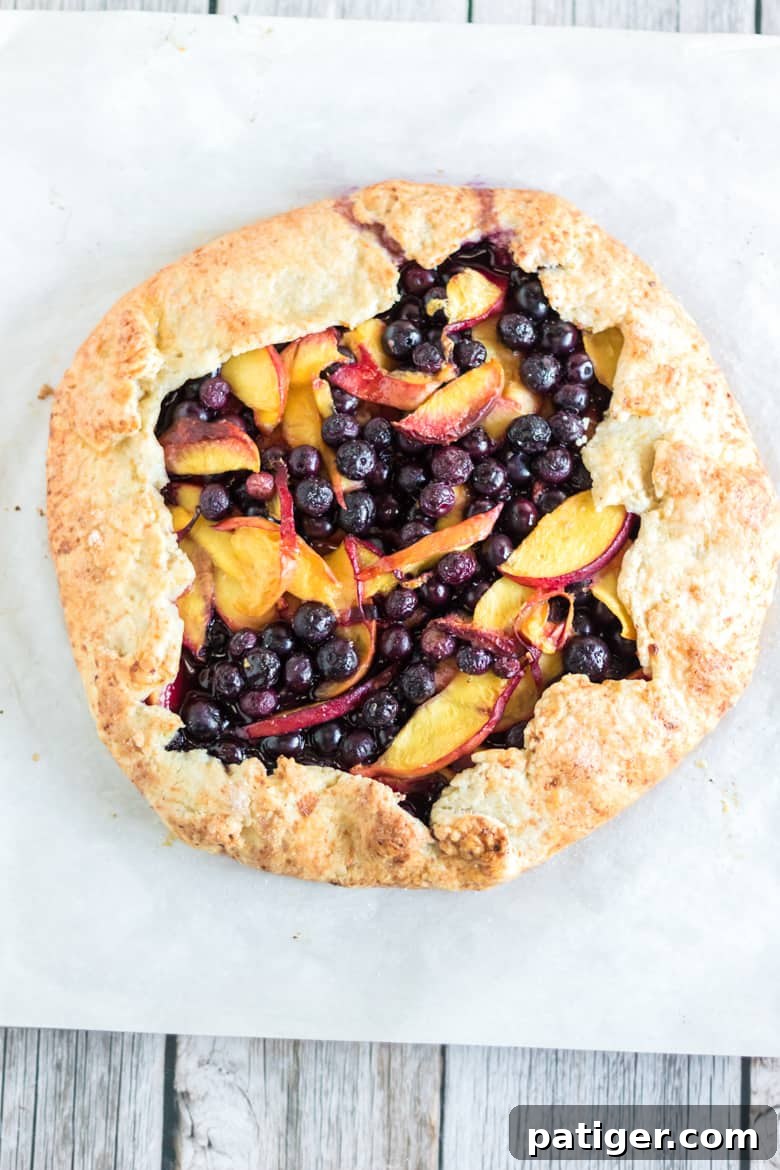 A freshly assembled peach blueberry galette, brushed with egg wash and sprinkled with sugar, ready for the oven.