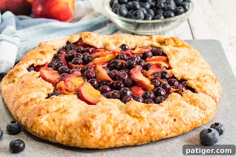 Freshly baked Peach and Blueberry Galette cooling on a rack, showcasing its golden crust and bubbling fruit filling.