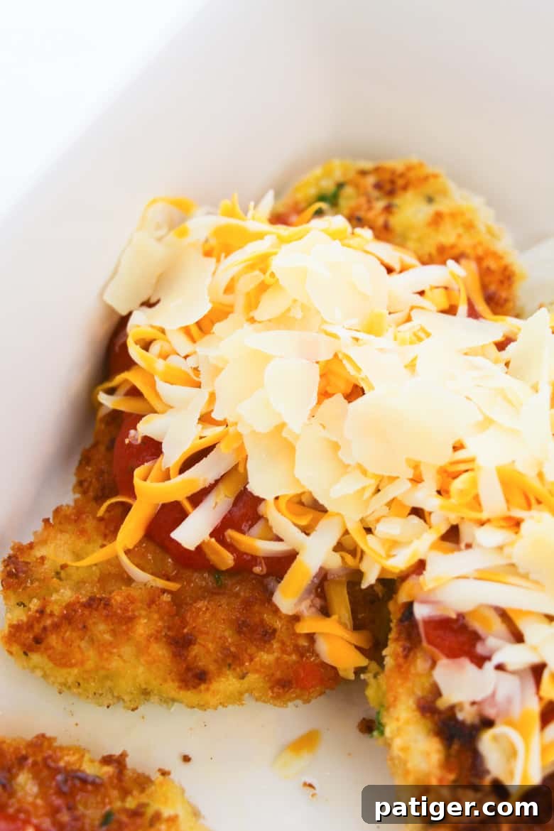 Topping chicken parm with sauce and cheese before baking