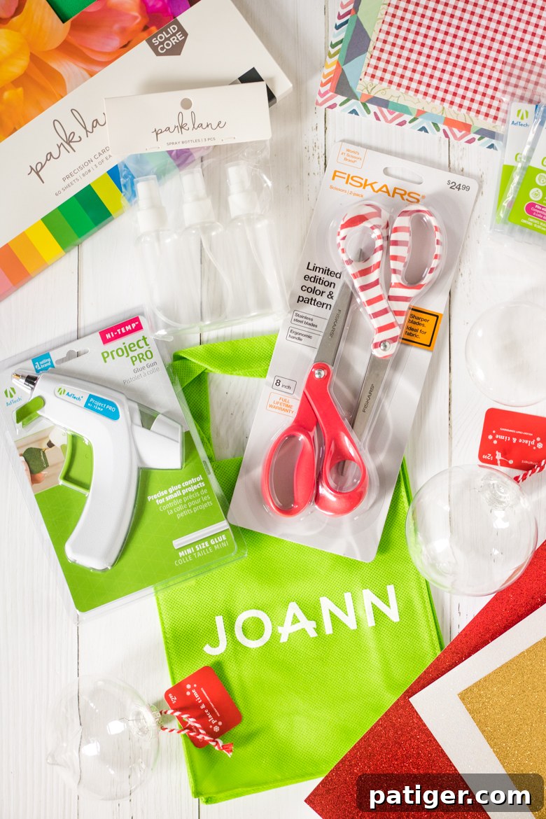 Craft supplies from Joann: A flat lay of various colorful cardstock and scrapbook papers, clear plastic ornaments, scissors, and a hot glue gun, all sourced from Joann.