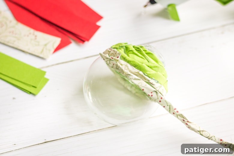 How to make twisted paper ornaments: A close-up of an ornament being covered with twisted paper strips, showing the hot gluing process.
