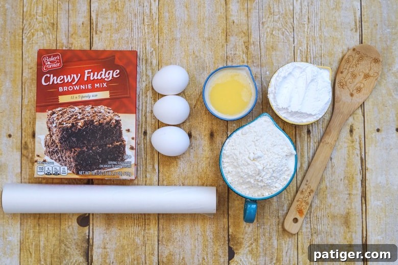 Ingredients for Brownie Mix Crinkle Cookies: Brownie mix, eggs, melted butter, flour, powdered sugar, with parchment paper and a wooden spoon nearby.